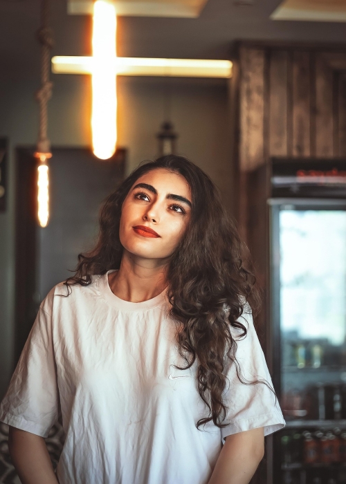 The Mesmerizing Beauty of a Woman Illuminated by a Unique Cross-Shaped Light Fixture