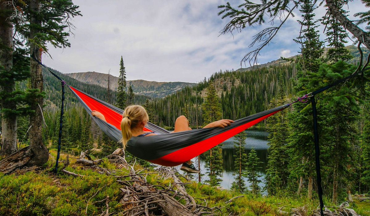 Tranquil Moments: Woman on Hammock by River in the United States - A Captivating Scene by Zach Betten